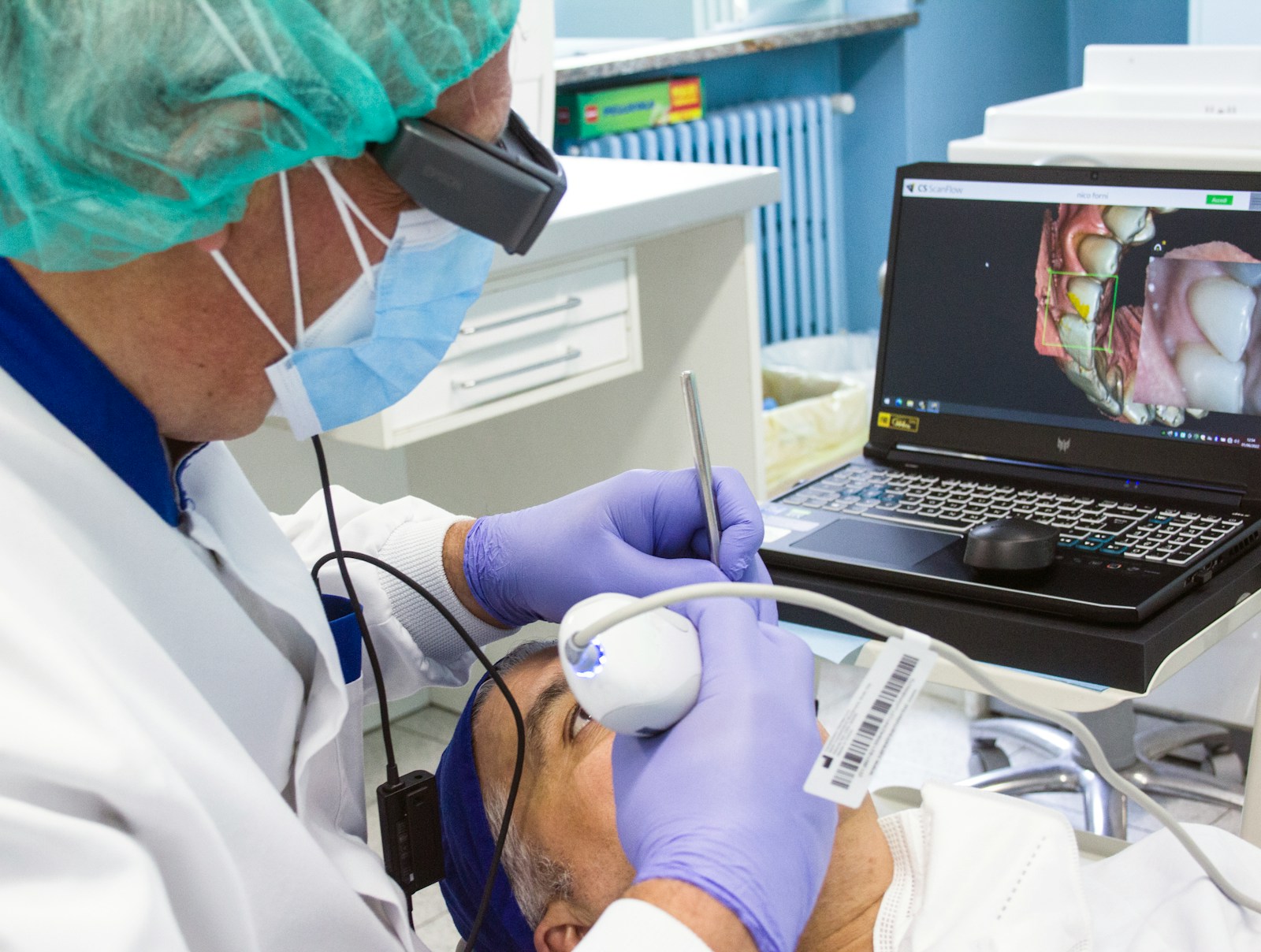 Dentista consultando imagem intraoral no notebook durante o atendimento